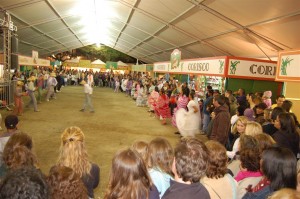 Imagem de barracão montado para o festival da Pinga de Paraty, com as barracas dos produtores em volta e um espaço grande com a população dançando quadrinha com roupas típicas de festa caipira